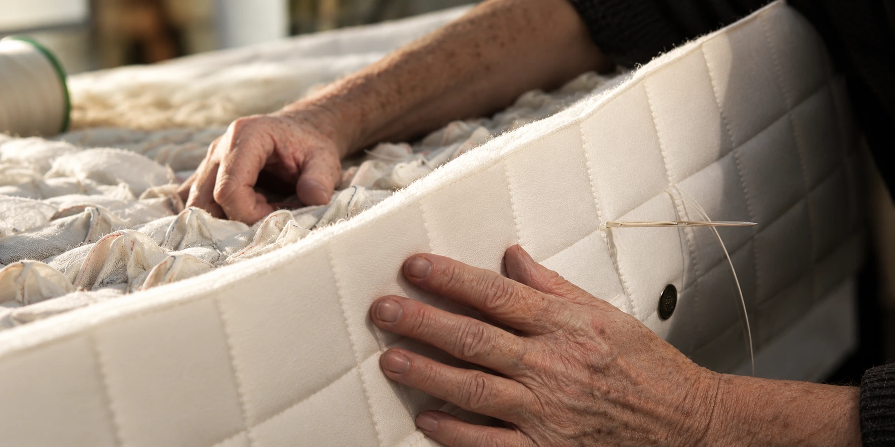 Artisan hand-finishing a natural wool mattress
